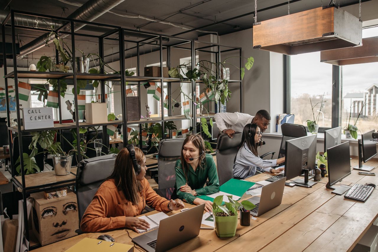 Group of diverse call center professionals working and collaborating in a modern office setting.